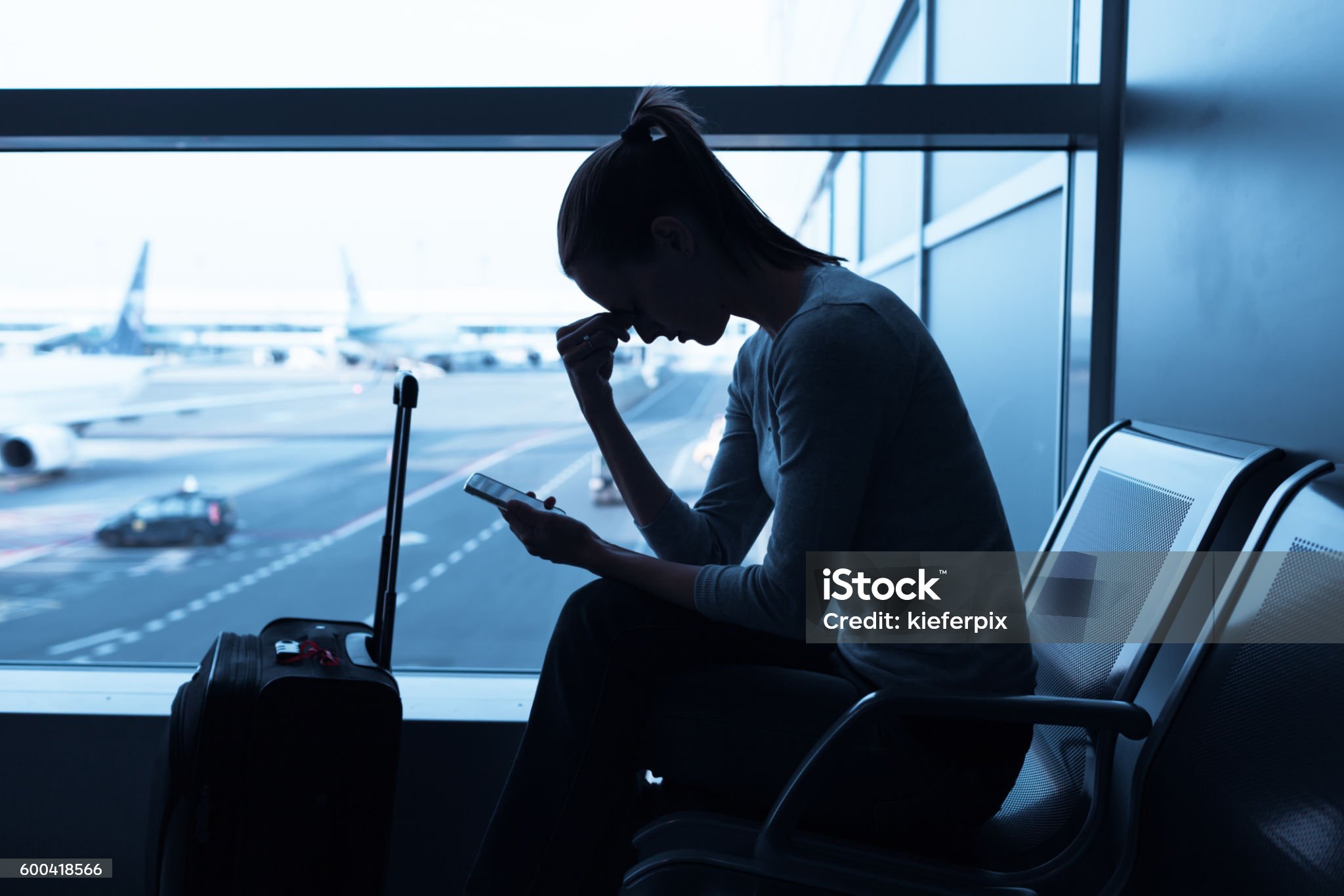 Woman looking at phone while waiting at airport gate