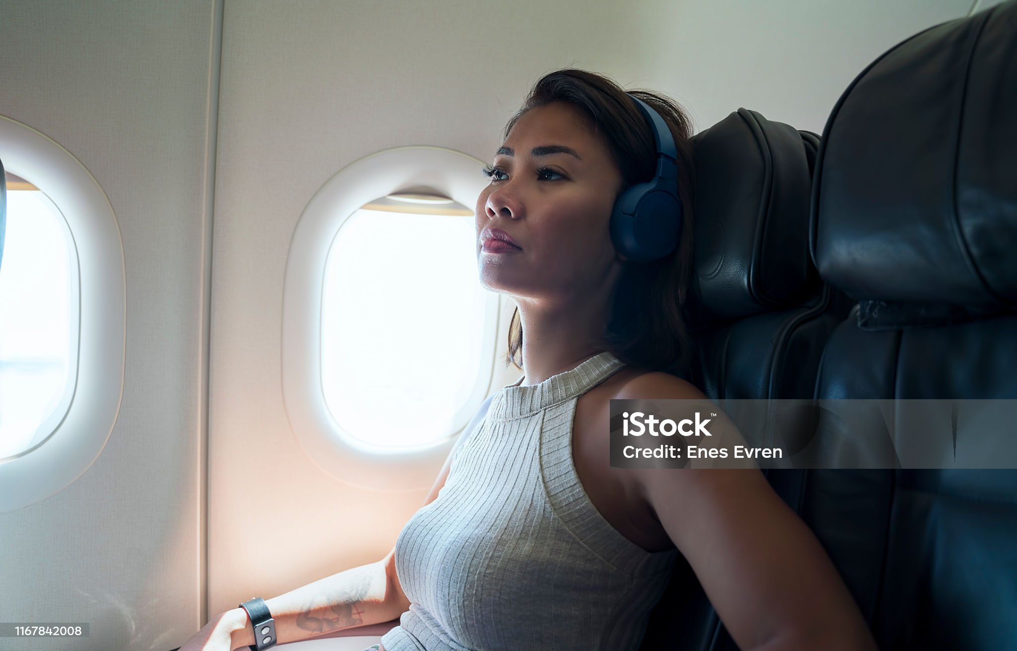 Woman relaxing in airplane seat with blue neck pillow during flight