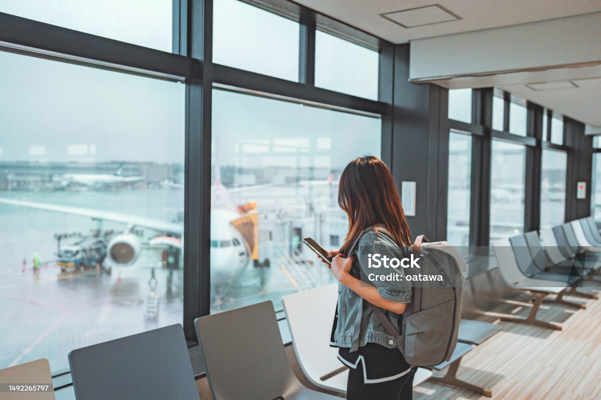 Woman with backpack looking at phone in airport terminal