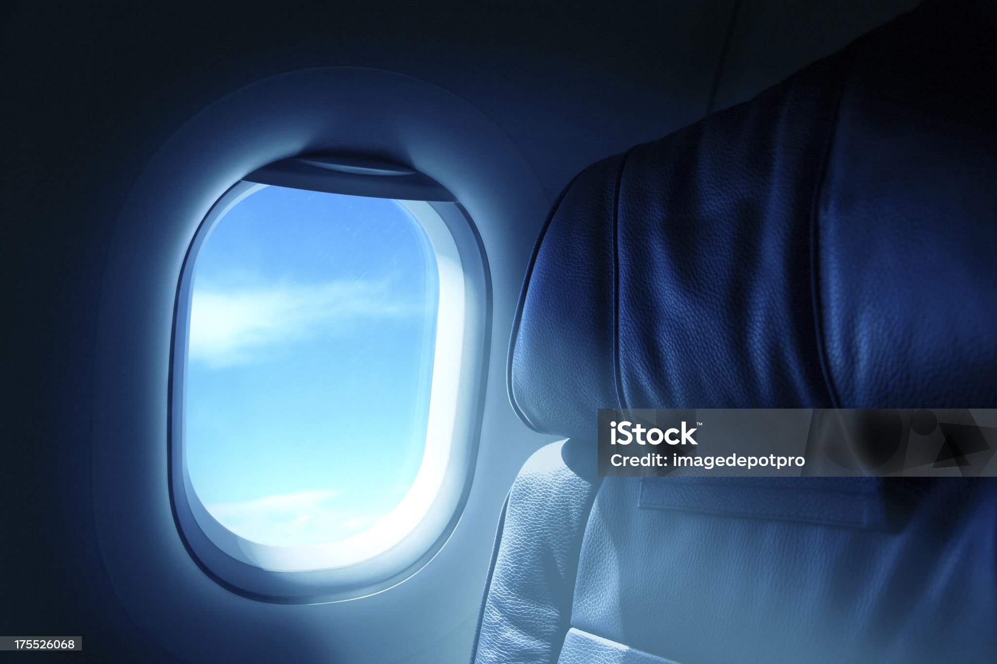 airplane window with blue sky view and dark interior cabin