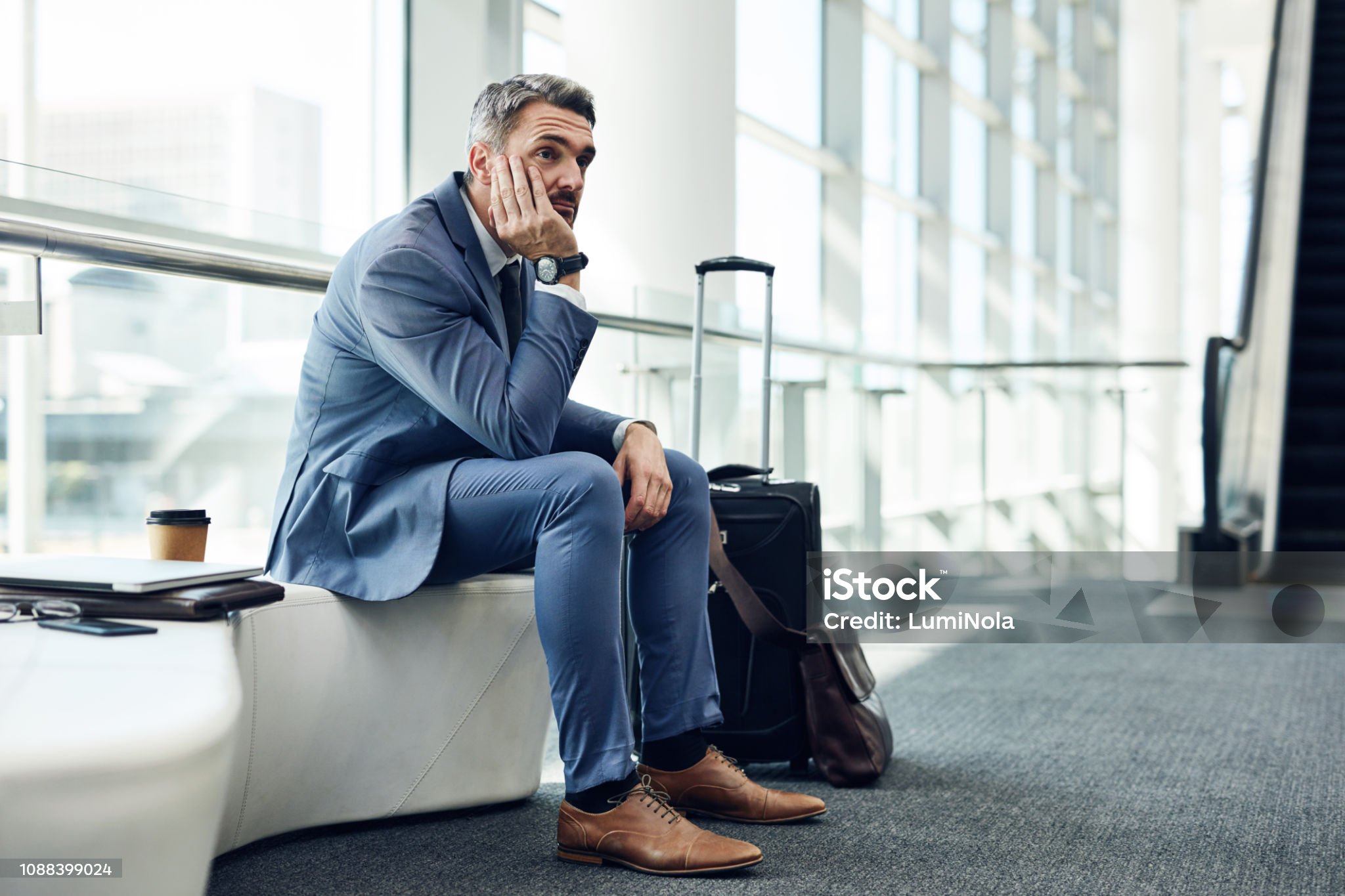 Businessman in suit looking worried while waiting at airport